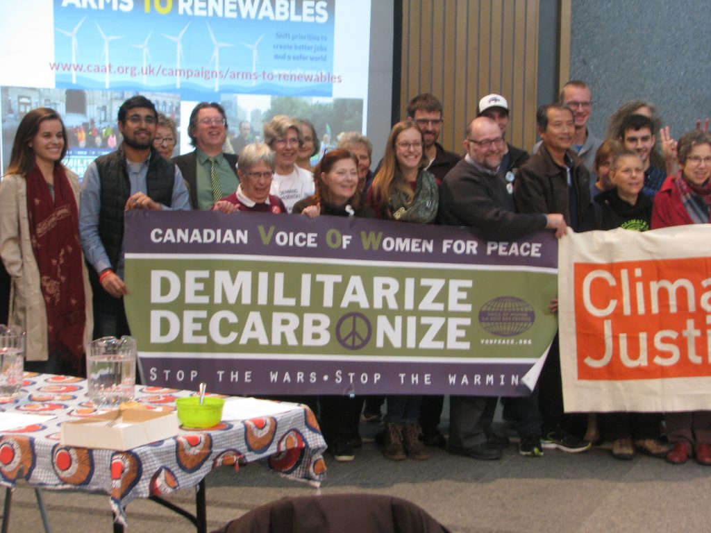 People holding banners "Demilitarize Decarbonize"